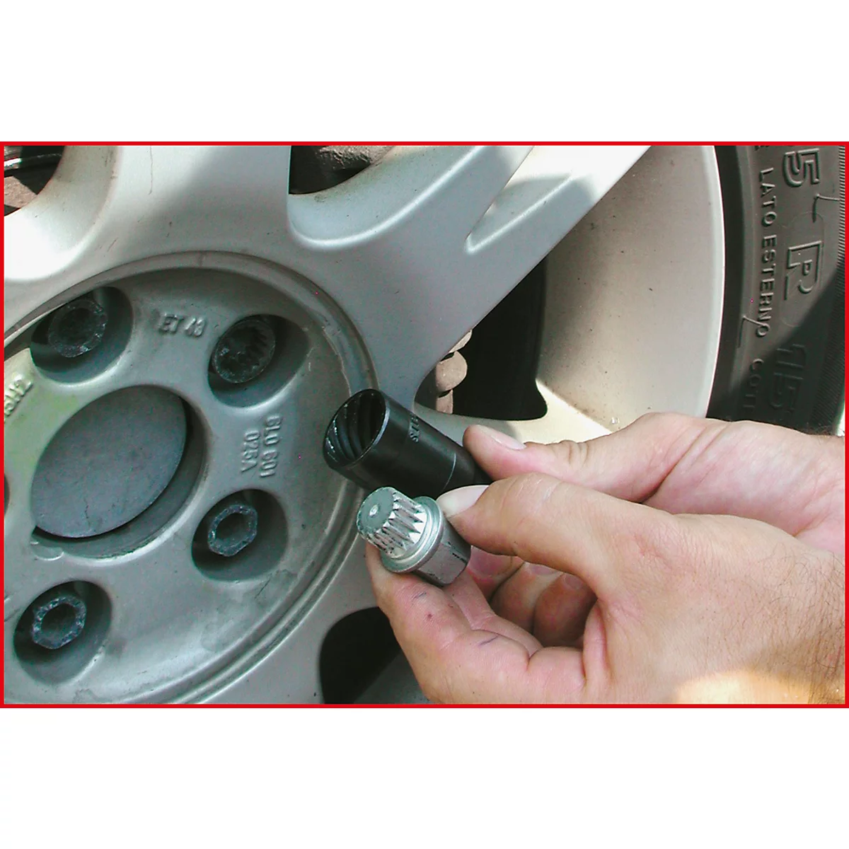 Nahaufnahme einer Hand, die Radmuttern entfernt. Werkzeug und Rad im Detail.